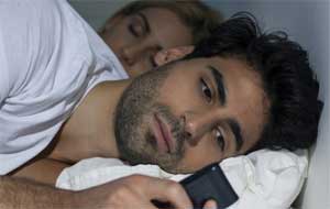 casal na cama com telemóvel
